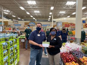 Two people standing in a grocery store with masks on, representing the partnership between the Sprouts Healthy Communities Foundation and SKSF through a grant.