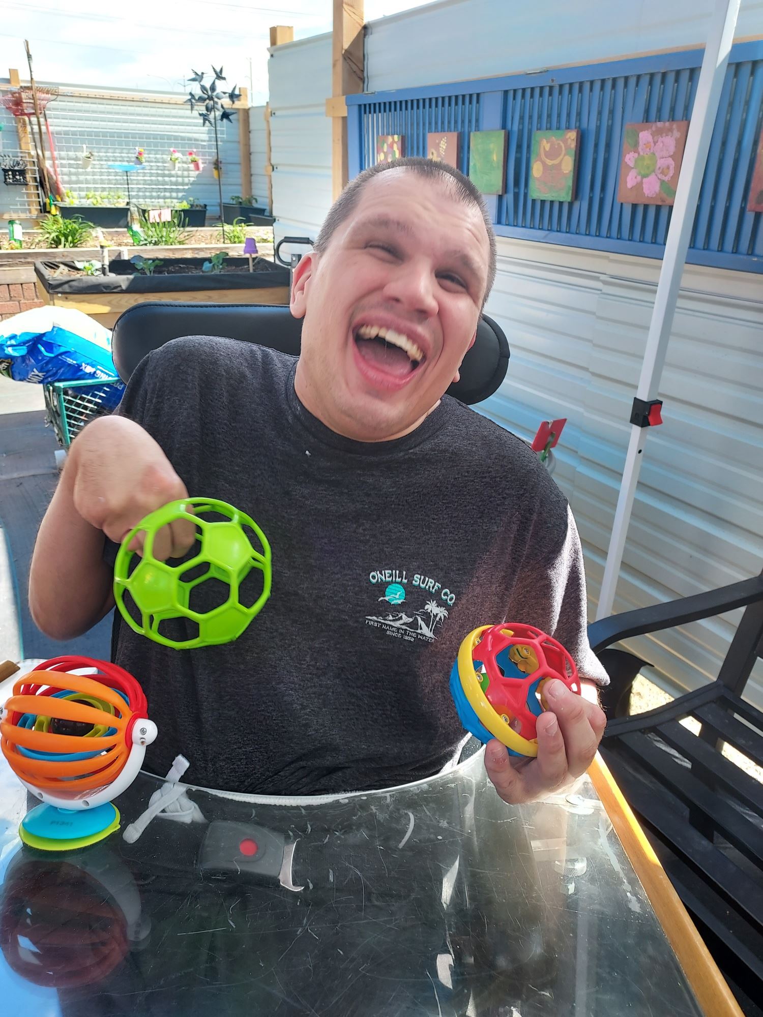 An adult man holding a set of toys at a table during an Adult Services for people with disabilities session.