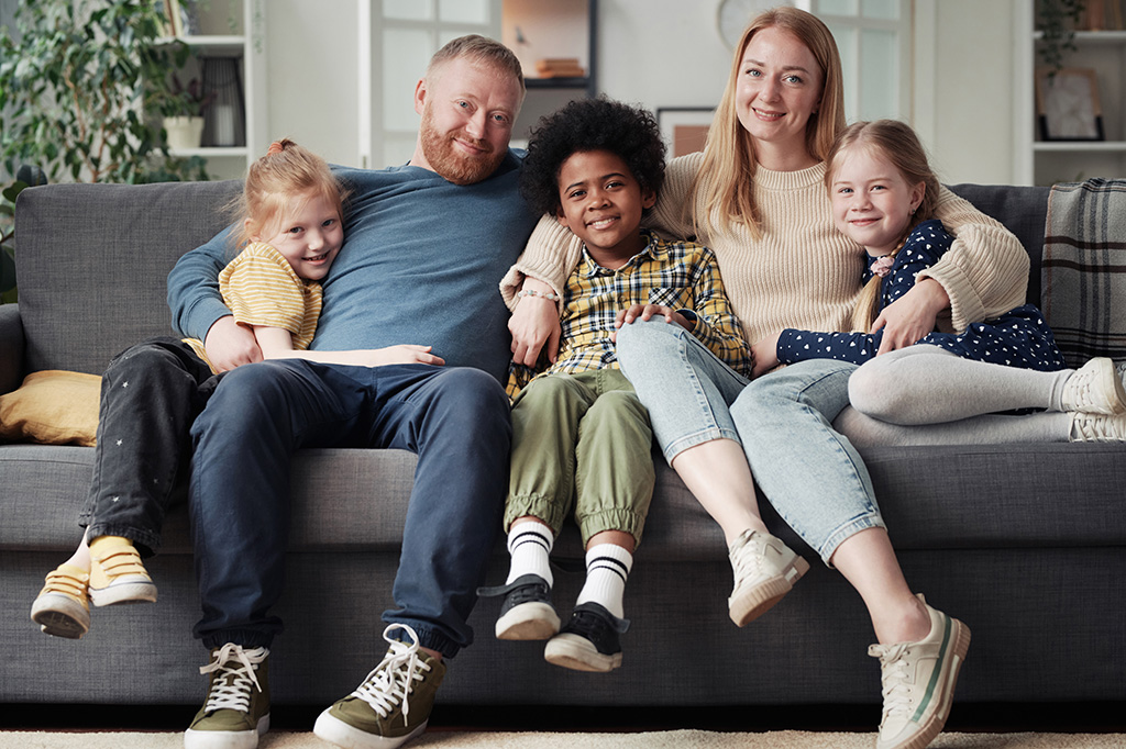 A family is sitting on a couch in a living room while providing respite foster care.