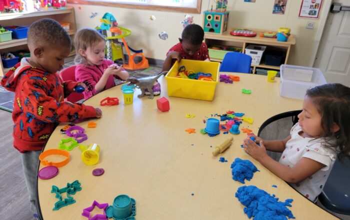 A group of children with disabilities playing with colored sand at a table, supervised by adults
